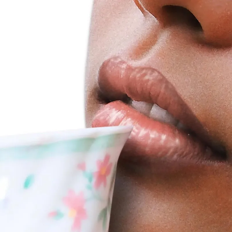 Nahaufnahme von Lippen, die an einer Tasse mit Blumenmuster nippen.