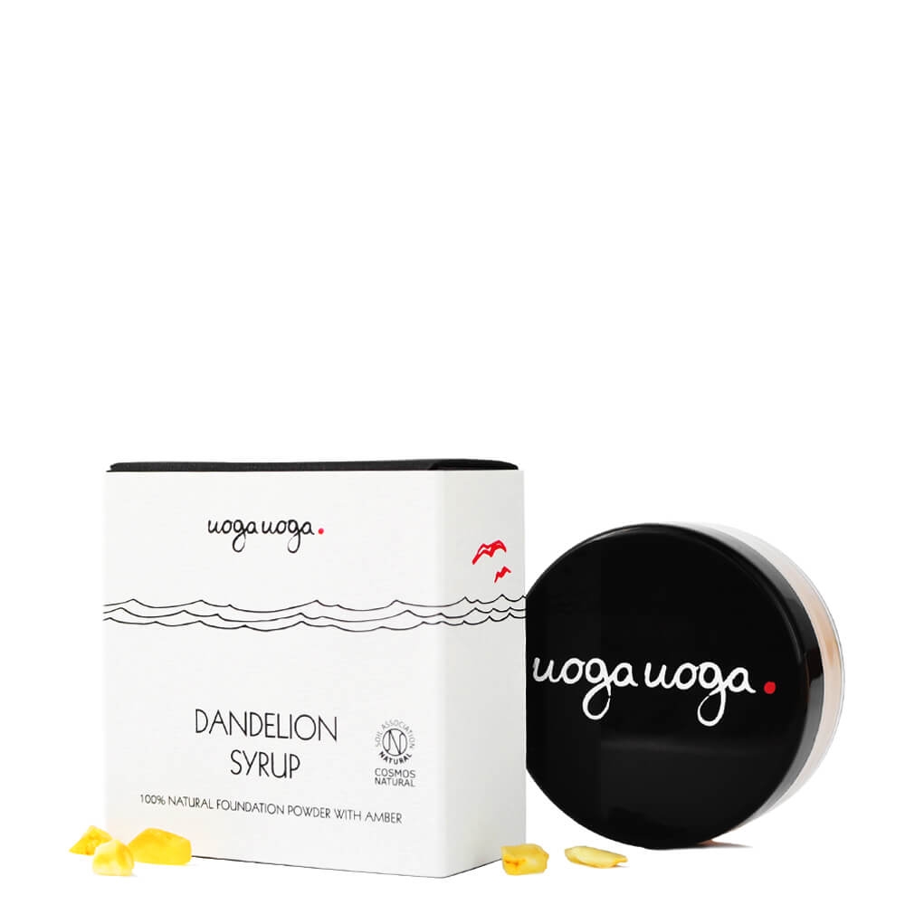 Woga Woga Dandelion Syrup Foundation-Puder mit Bernstein, Verpackung und Dose, auf weißem Hintergrund, gelbe Blütenblätter daneben.