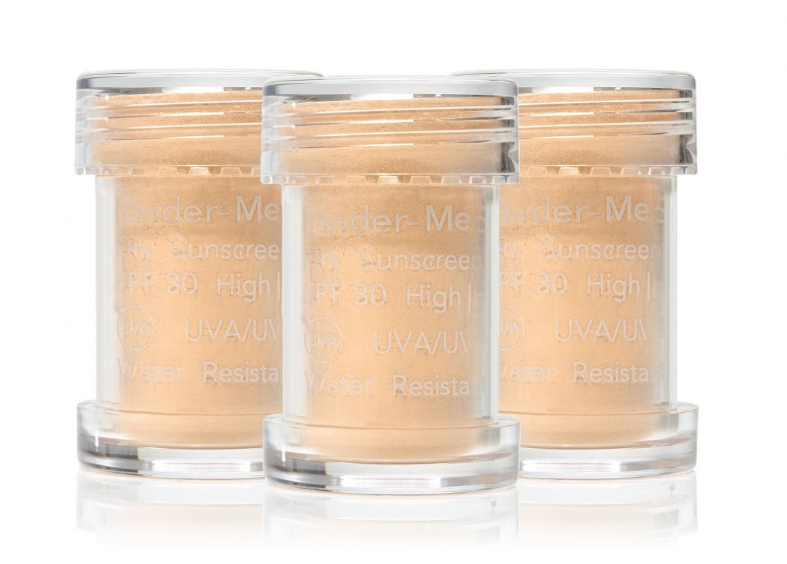 Drei durchsichtige Behälter mit losem Puder, beschriftet mit 'Powder-Me SPF 30 High UVA/UVB Water Resistant'.