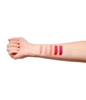 Ein ausgestreckter Arm mit sechs verschiedenen Lippenstiftfarben auf dem Unterarm aufgetragen.