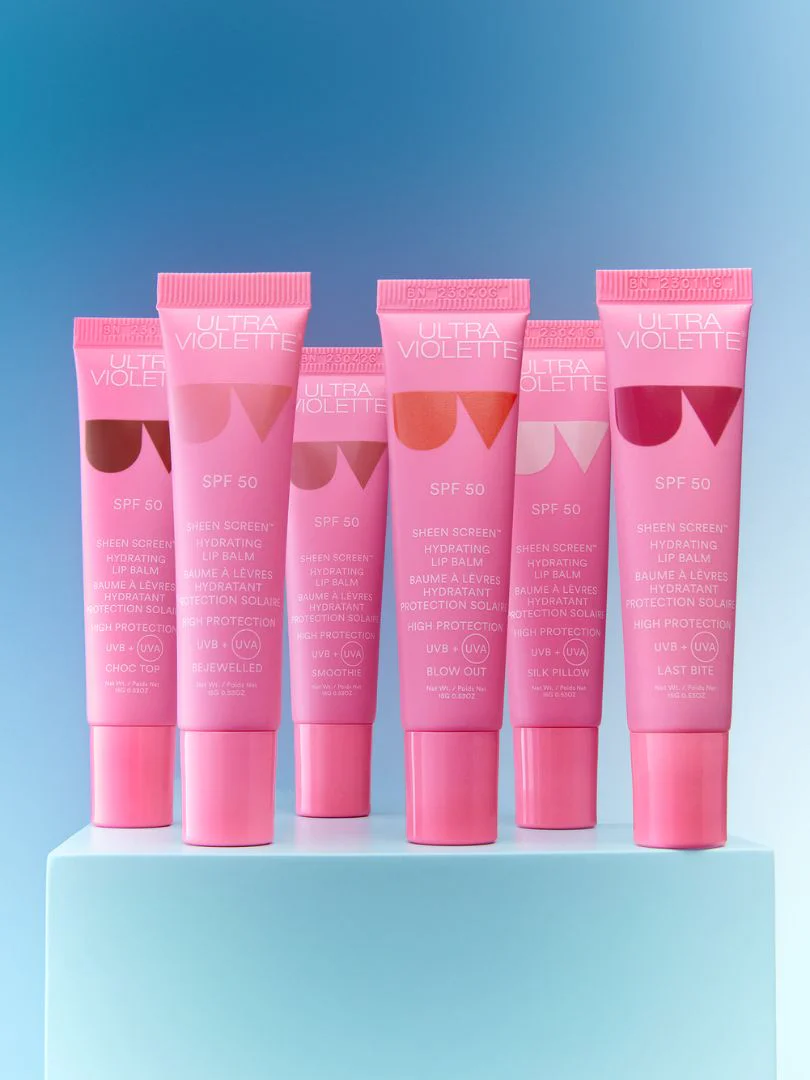 Fünf rosa Tuben Ultra Violette Sheen Screen SPF 50 Lippenbalsam auf blauem Hintergrund.