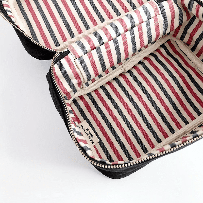 bag-all-beauty-box-klein-ohne-schrift-schwarz_2_optimizedb7mWKFvlUXQqs Schwarze Kosmetiktasche mit rot-schwarz-weiß gestreiftem Innenfutter, geöffnet, auf weißem Hintergrund.