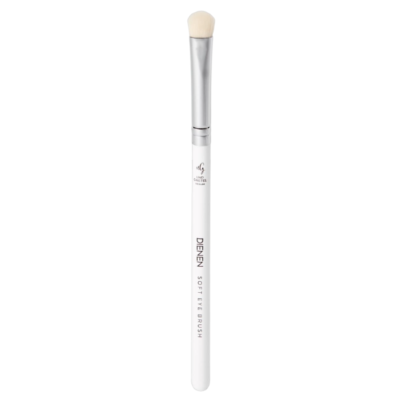 Ein weißer Schminkpinsel mit silbernem Griff und weichen Borsten, beschriftet mit 'UND GRETEL DIENEN SOFT EYE BRUSH'.