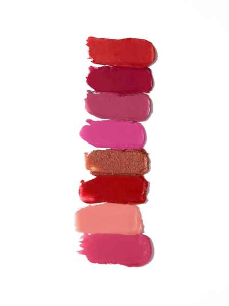 Sieben Lippenstiftfarben in verschiedenen Rottönen und Rosa auf weißem Hintergrund.